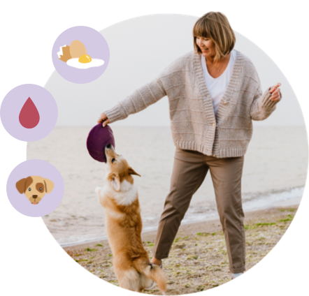 Woman playing tug-o-war on the shore with her dog