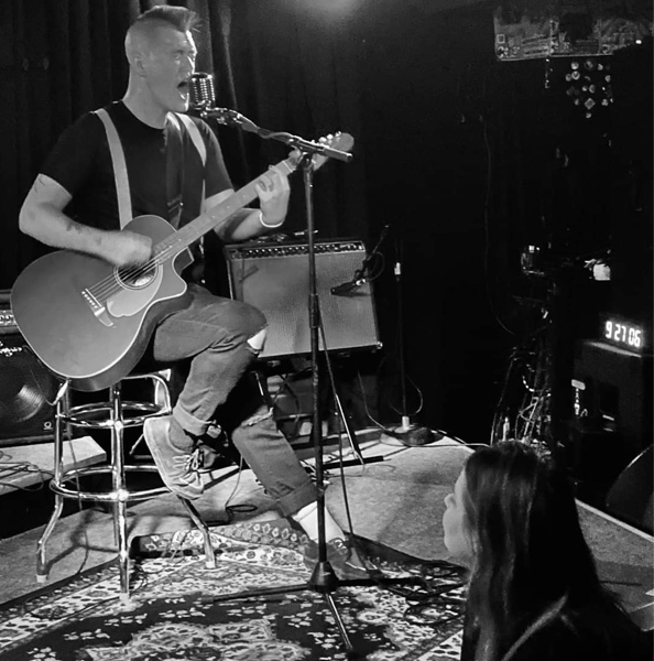 Chris Chamberlain-Nonan on stage, performing with his band. 